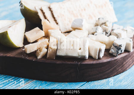 Käseplatte mit blauen Käse, Quark und Käse auf rustikalen Holzbrett serviert mit Birne und Cracker Stockfoto