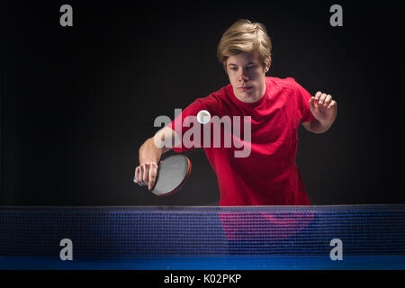 Junger Mann tennis player im Spiel auf schwarzem Hintergrund Stockfoto