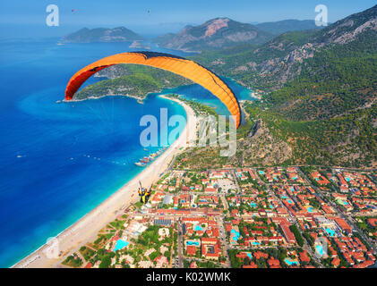 Gleitschirmfliegen in den Himmel. Gleitschirm Tandem über das Meer mit blauem Wasser und Berge im sonnigen Tag fliegen. Luftaufnahme von Gleitschirm und Blau La Stockfoto