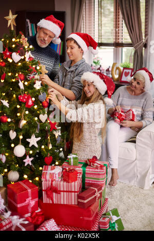 Ganze Familie Dressing einen Weihnachtsbaum Stockfoto