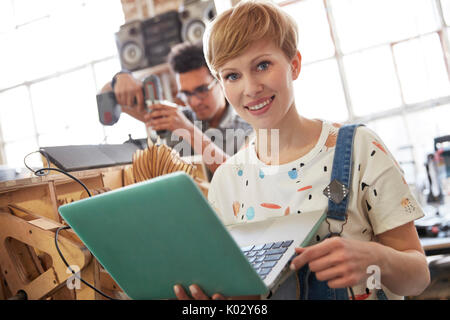 Portrait lächelnd weibliche Designer mit Laptop in der Werkstatt Stockfoto