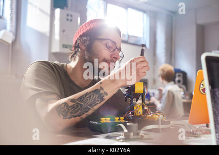 Junge männliche Designer Montage Robotik in der Werkstatt konzentriert Stockfoto