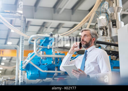 Männliche Supervisor mit digitalen tablet Gespräch am Handy in der Factory Stockfoto