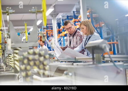 Supervisor und Ingenieur über Pläne in der Faseroptik Factory Stockfoto