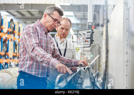 Männliche Vorgesetzte und Mitarbeiter Prüfung Maschinen in der Faseroptik Factory Stockfoto