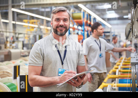 Porträt Lächeln, selbstbewusste männliche Supervisor mit Zwischenablage in Fiber Optik Factory Stockfoto