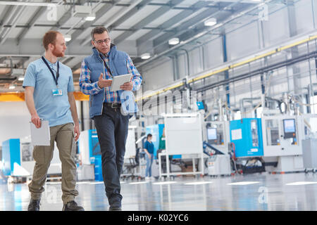 Männliche Vorgesetzte und Mitarbeiter mit digitalen Tablet sprechen und Wandern in der Factory Stockfoto