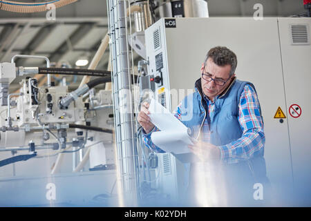 Männliche Supervisor mit Zwischenablage Gespräch am Handy in der Factory Stockfoto