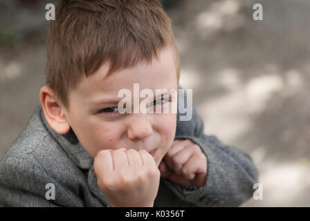 Lustige kleine Junge droht mit Fäusten Stockfoto