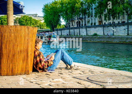 Ein Mann liest während einer Bootsfahrt auf der Seine auf einem schönen Sommern' Tageskarten Stockfoto