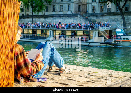 Ein Mann liest während einer Bootsfahrt auf der Seine auf einem schönen Sommern' Tageskarten Stockfoto