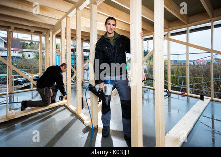 Tischler Holding Bohrers, während Kollege Arbeiten am Bau Stockfoto