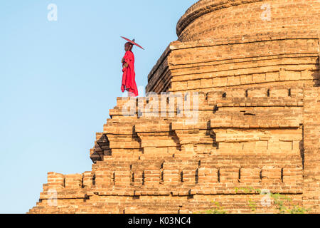 Bagan, Mandalay Region, Myanmar (Burma). Ein junger Mönch auf einem Stupa. Stockfoto