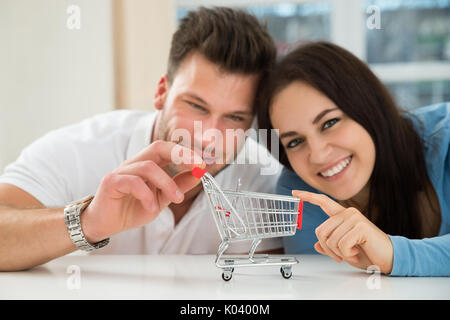 Nahaufnahme des Lächelnden jungen Paar mit Miniatur leer Warenkorb Stockfoto