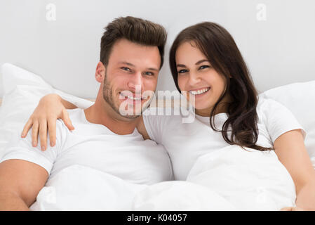 Portrait von glückliches junges Paar auf dem Bett zu Hause Stockfoto