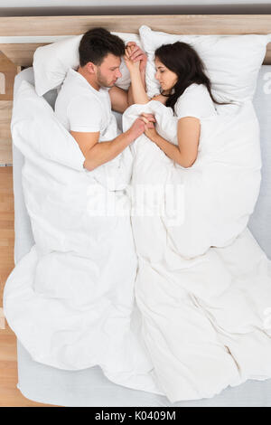 Hohe Betrachtungswinkel von Paar hält jedes Anderen Schlafen auf Bett Stockfoto