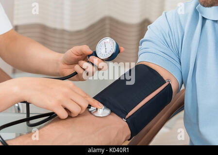 In der Nähe der weiblichen Arzt Kontrolle Blutdruck der männlichen Patienten Stockfoto