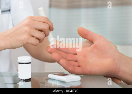 In der Nähe der weiblichen Arzt mit lanzettfischchens auf Mann am Schreibtisch, In der Klinik Stockfoto