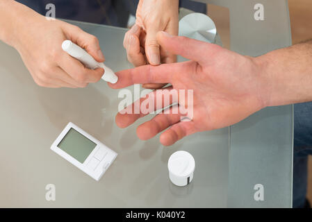 In der Nähe der weiblichen Arzt mit lanzettfischchens auf Mann am Schreibtisch, In der Klinik Stockfoto