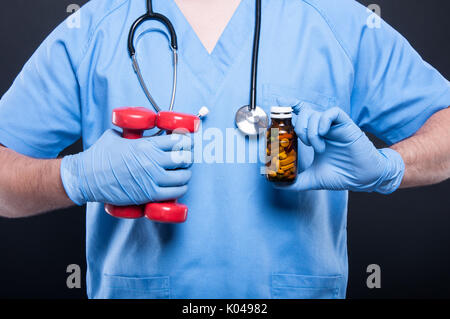 In der Nähe von Doktor mit Hanteln und eine Flasche Pillen auf schwarzem Hintergrund Stockfoto