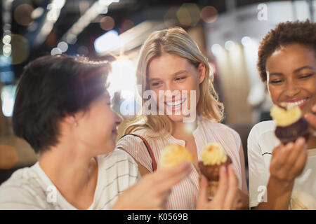 Junge Frauen essen Cupcakes Stockfoto