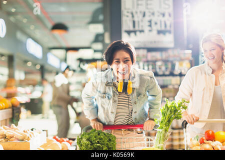 Portrait verspielte junge Frau mit Warenkorb Einkaufen im Markt Stockfoto