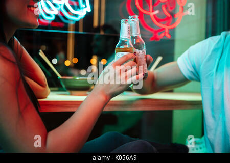 7/8 Image der Jungen multiethnischen fröhliches Paar sitzt im Cafe trinken Bier. Stockfoto
