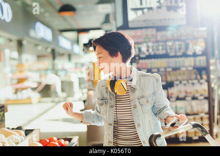 Junge Frau mit Kopfhörer Surfen, Einkaufen auf dem Markt Stockfoto