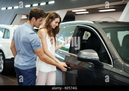 Schöne junge Paare auf der Suche nach einem neuen Auto in der Händlerniederlassung showroom Stockfoto