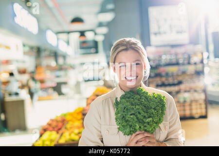 Portrait lächelnde junge Frau mit Bündel von Kale in Lebensmittelgeschäft Markt Stockfoto