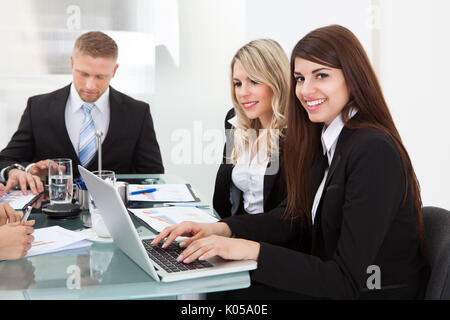 Porträt von lächelnden Geschäftsfrau mit Kollegen treffen im Büro sitzen Stockfoto