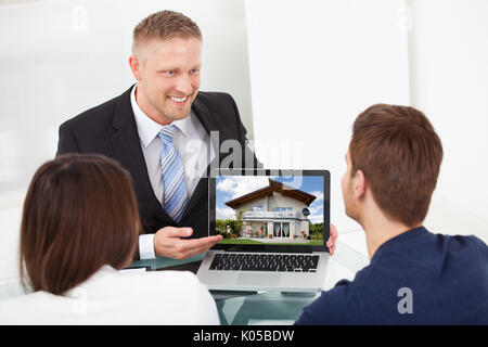 Lächelnd Berater zeigen Haus Bild auf Laptop am Schreibtisch zu koppeln Stockfoto