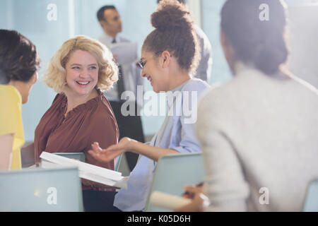 Lächelnd Geschäftsfrauen Unterlagen darüber beraten in der Konferenz Publikum Stockfoto