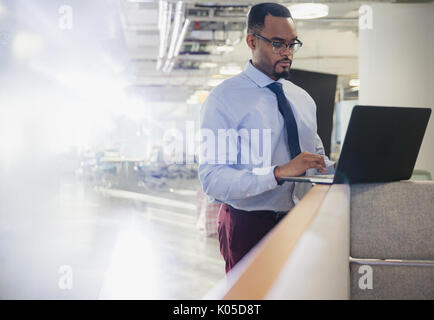 Geschäftsmann mit Laptop an der Bürozelle Wand Stockfoto