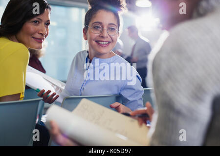 Lächelnd Geschäftsfrauen Unterlagen darüber beraten in der Konferenz Publikum Stockfoto