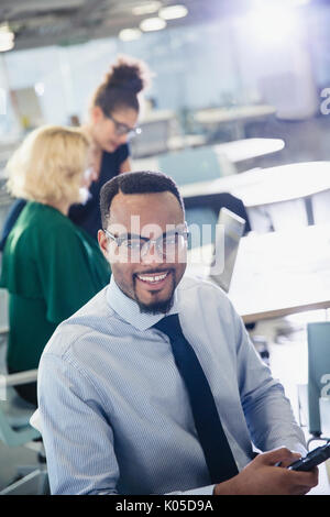 Porträt Lächeln Geschäftsmann SMS mit Handy im Büro Stockfoto