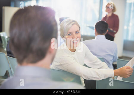 Lächelnd Geschäftsfrau im Gespräch mit Unternehmer in Konferenz Publikum Stockfoto