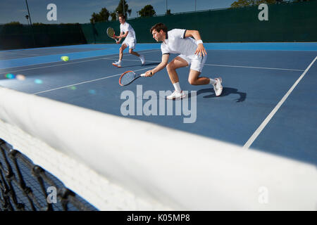 Junge männliche Tennis Doubles Spieler Tennis spielen auf Tennisplatz Stockfoto