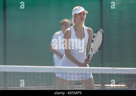 Junge weibliche Tennisspieler bereit, mit Tennisschläger bei Net fokussiert Stockfoto