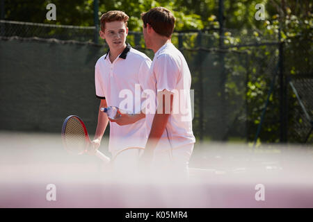 Männliche tennis Spieler mit Tennisschläger sprechen an sonnigen Tennisplatz Stockfoto