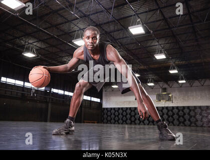 Portrait selbstbewussten jungen männlichen Basketballspieler Dribbling den Ball auf Gericht im Gymnasium Stockfoto