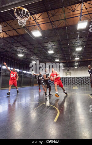Junge männliche Basketballspieler Basketball spielen auf Gericht im Gymnasium Stockfoto