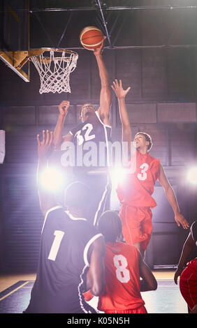 Junge männliche Basketballspieler Basketball spielen im Gymnasium Stockfoto