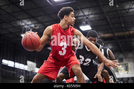 Junge männliche Basketball player Dribbling den Ball, das Spiel in der Sporthalle Stockfoto