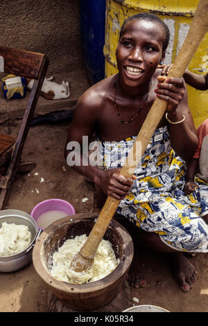 Côte d'Ivoire, Elfenbeinküste, Westafrika. Junge Frau stampfenden Süßkartoffeln für die nächste Mahlzeit. Lolobo Dorf in der Nähe von Bouaké. Stockfoto