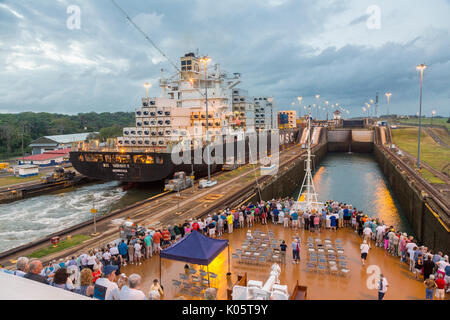 Panama Canal, Panama. Containerschiff Eingabe erste Sperre, Karibischen Seite, Richtung Lake Gatun, Passagiere auf Kreuzfahrtschiffen beobachten. Stockfoto