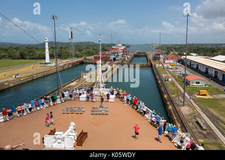 Panama Canal, Panama. Die Passagiere an Deck zusehen, wie Schiff Transite drei Ebenen des Gatun Schleusen auf dem Weg in die Karibik. Auf der linken Seite, Container schiff Stockfoto