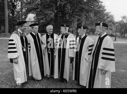 Ganzkörper-Porträt von Präsident Steven Muller, Professor Daniel K Ludwig, Musiker Leonard Bernstein, und Professor Milton Reder, und zwei andere in Gap und Kleid auf einem College quad für Johns Hopkins 1980 Beginn, 1980. Stockfoto