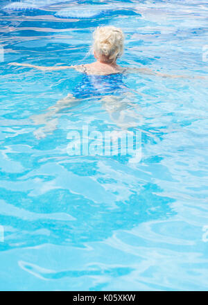 Ältere Frau schwimmen im Außenpool Stockfoto