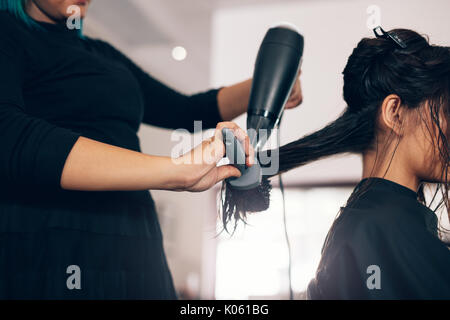 Weibliche Friseur mit Gebläse und Pinsel zu trockenes Haar. Friseur mit Trockner bei Frau nasse Haar im Salon. Stockfoto